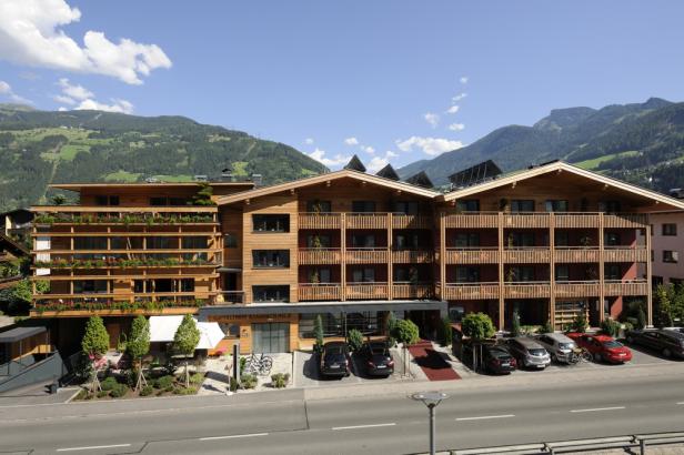 Ein modernes Hotel mit Holzbalkonen vor einer Bergkulisse.