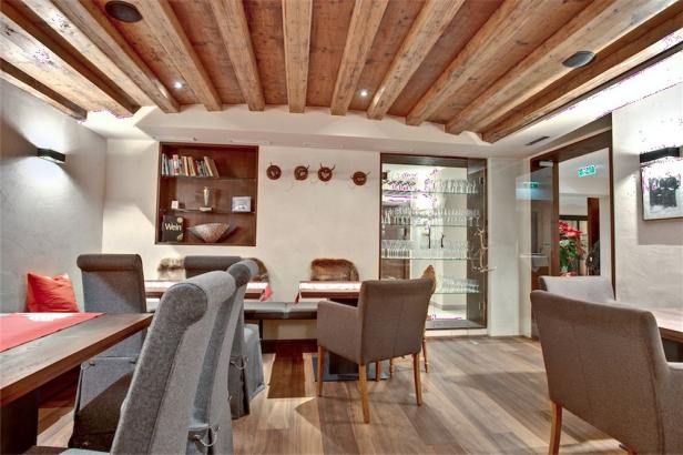 Ein Speisesaal mit Holzbalkendecke und gedeckten Tischen.