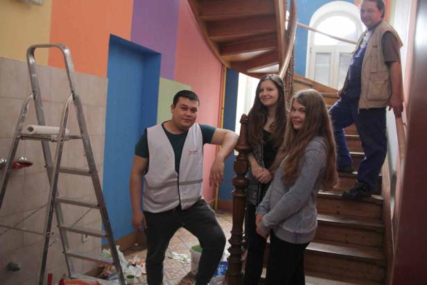 Eine Gruppe von Menschen steht in einem renovierten Treppenhaus mit bunten Wänden.