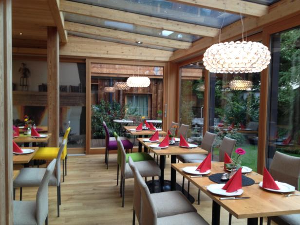 Ein helles Restaurant mit Holzbalken und gedeckten Tischen.