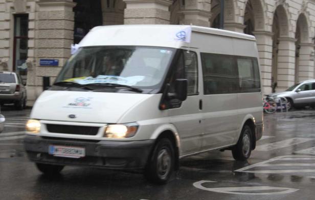 Ein weißer Ford Transit fährt auf einer nassen Straße.