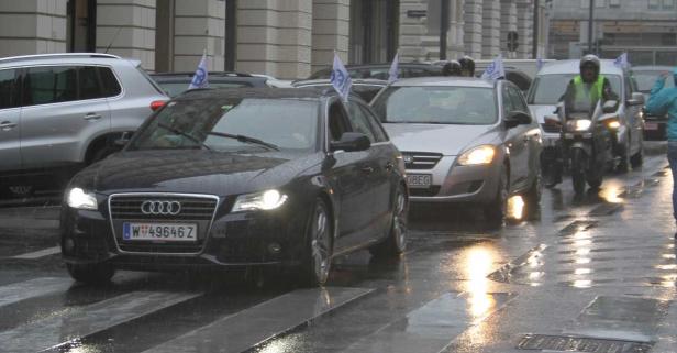 Autos mit Flaggen fahren auf regennasser Straße.