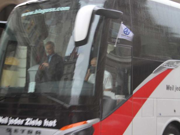 Ein Reisebus der Firma Blaguss mit einem Fahrer und einer Friedensflagge.