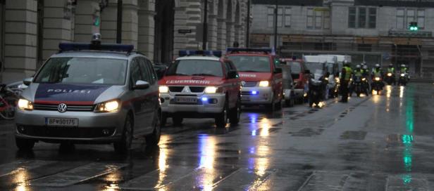 Auf einer nassen Straße stehen Einsatzfahrzeuge der Polizei und Feuerwehr, gefolgt von Motorrädern.