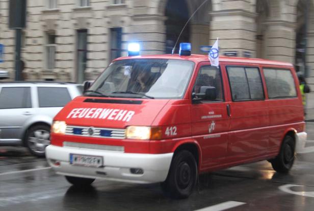 Ein roter VW-Bus der Wiener Feuerwehr mit Blaulicht fährt durch die Stadt.