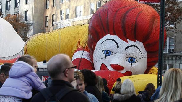 Ein riesiger Ronald McDonald Ballon schwebt über einer Menschenmenge bei einer Parade.