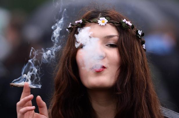 Eine junge Frau mit Blumenkranz raucht eine Zigarette.