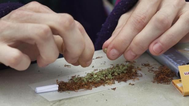 Eine Person rollt eine Zigarette mit Tabak und Cannabis.