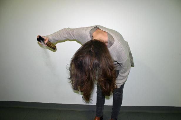 Eine Frau beugt sich nach vorne und sprüht Haarspray auf ihr Haar.