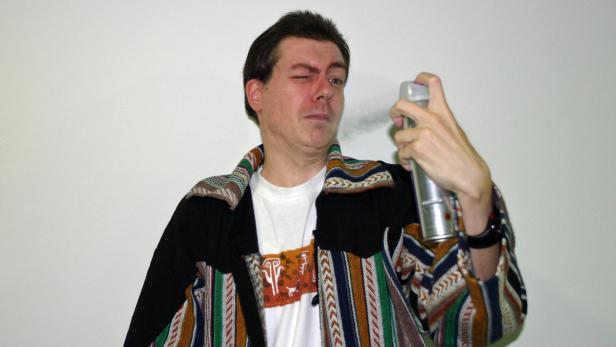 Ein Mann sprüht sich etwas aus einer Dose ins Gesicht.