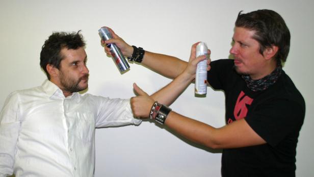 Zwei Männer zielen mit Sprühdosen aufeinander.