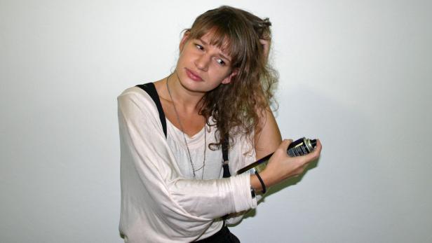 Eine Frau sprüht Haarspray in ihr lockiges Haar.