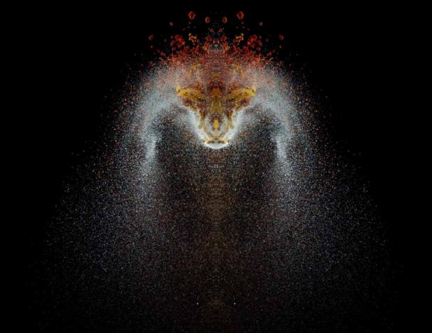 Eine symmetrische Explosion aus farbigem Pulver vor einem schwarzen Hintergrund.