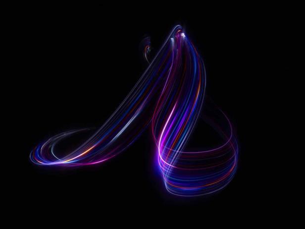 Mehrfarbige Lichtspuren bilden ein abstraktes Muster vor schwarzem Hintergrund.