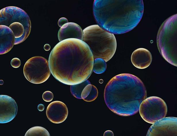 Viele bunte Seifenblasen schweben vor einem schwarzen Hintergrund.