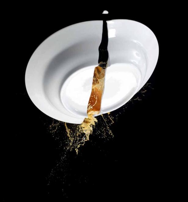 Eine zerbrochene weiße Schüssel, aus der eine gelbliche Flüssigkeit spritzt.