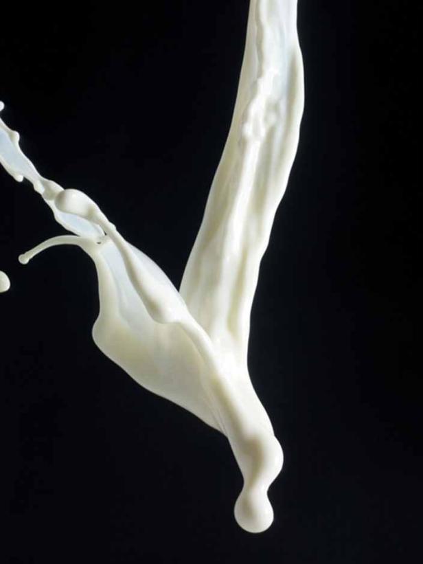 Ein Schuss Milch vor einem schwarzen Hintergrund.