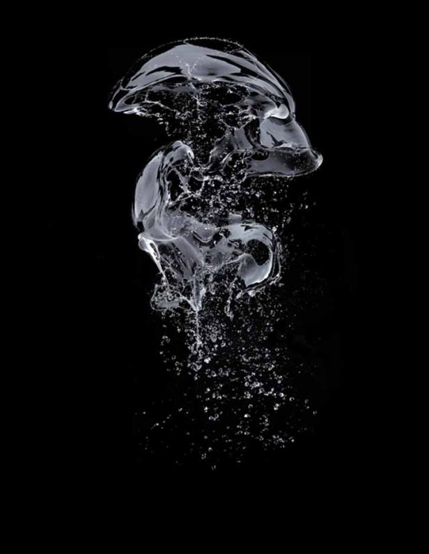 Ein Wassertropfen formt eine abstrakte Figur vor einem schwarzen Hintergrund.