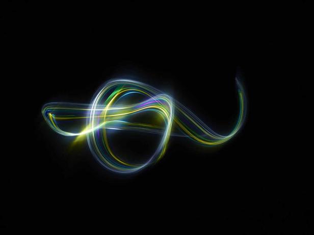 Mehrfarbige Lichtspuren bilden ein abstraktes Muster vor schwarzem Hintergrund.