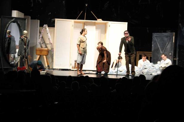 Eine Theaterszene mit mehreren Schauspielern auf einer Bühne.