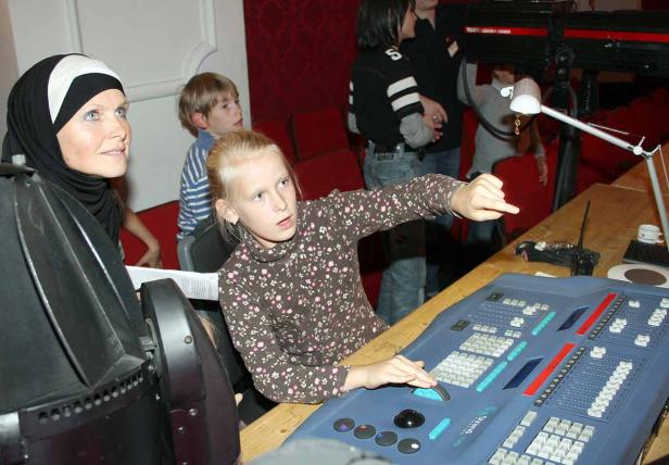 Ein Mädchen bedient ein Mischpult, während eine Frau mit Kopftuch zusieht.