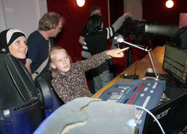 Ein Mädchen zeigt auf einen Scheinwerfer in einem Theater.