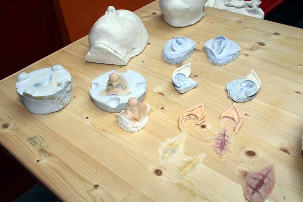 Auf einem Tisch liegen Gipsformen von Gesichtern, Ohren und Narben für Spezialeffekte.