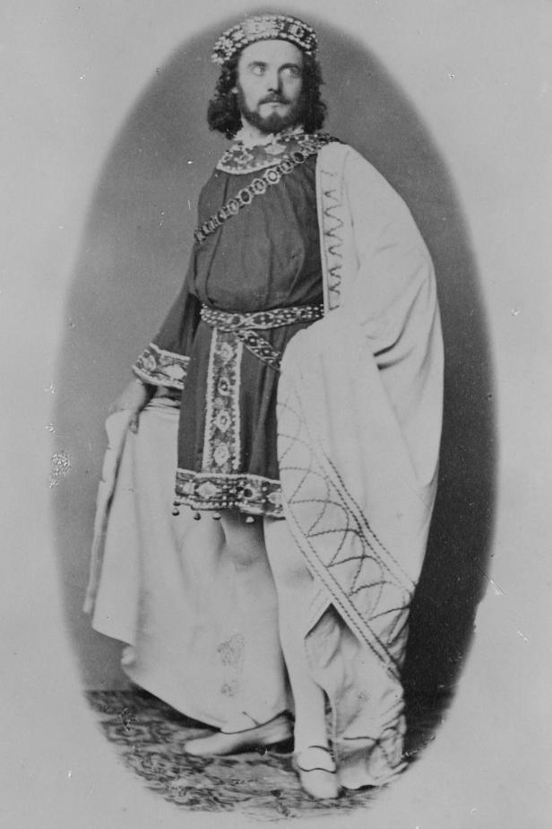 Ein Mann mit Bart und Krone, bekleidet mit einem verzierten Gewand.