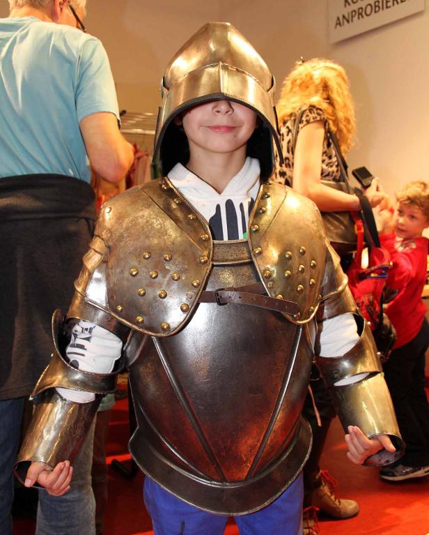 Ein Kind posiert in einer glänzenden Ritterrüstung mit Helm.