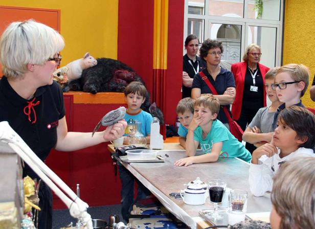 Eine Frau zeigt einer Gruppe von Kindern einen präparierten Vogel.