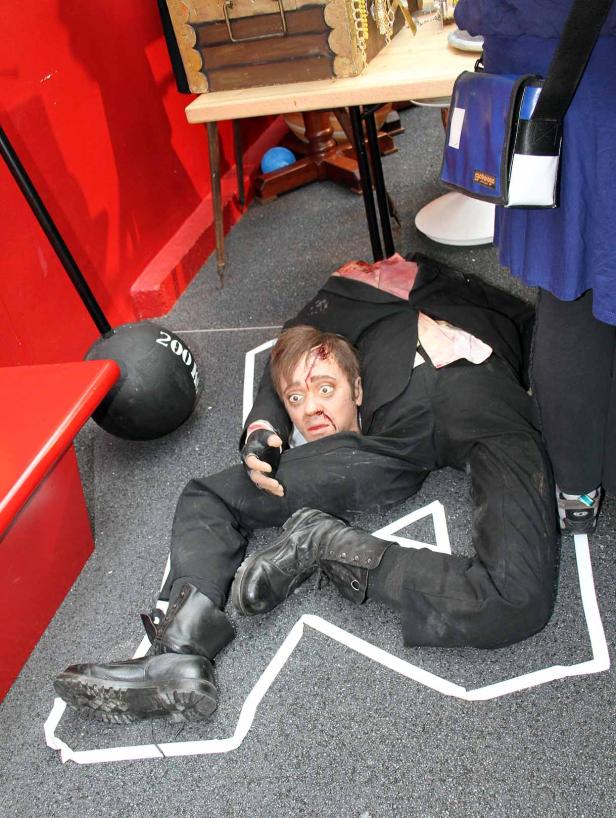 Ein Mann liegt mit blutigem Gesicht und Kopfverletzung auf dem Boden, umgeben von einer Kreideumrandung.