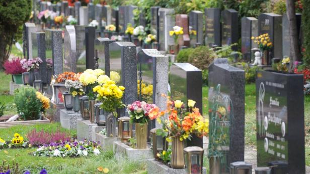 Ein Friedhof mit Grabsteinen, Blumen und Grablichtern.