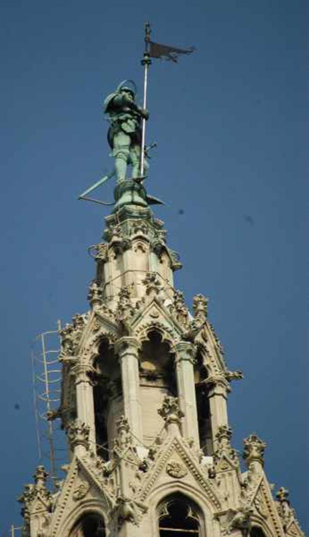 Die Statue eines Ritters mit Fahne auf der Spitze eines verzierten Gebäudes.