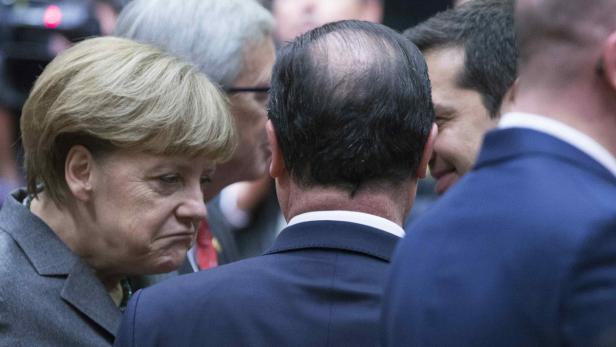 Angela Merkel umringt von mehreren Personen in Anzügen.