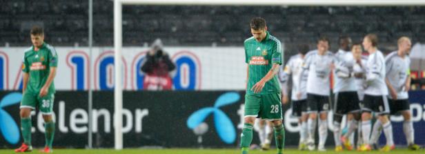 Zwei Fußballspieler in grünen Trikots stehen während eines Spiels auf dem Feld.
