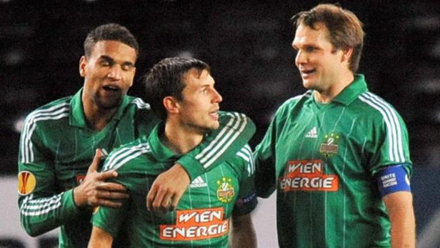 Drei Fußballspieler von Rapid Wien in ihren grünen Trikots stehen zusammen.