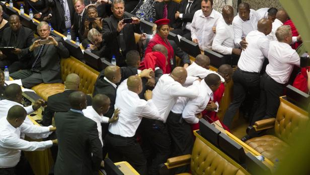 In einem Parlament kommt es zu einer Auseinandersetzung zwischen mehreren Personen.
