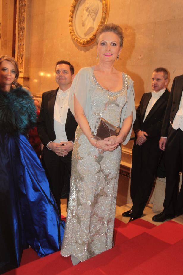 Eine Frau in einem eleganten, silbernen Kleid auf einem roten Teppich.