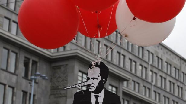 Ein Pappbild mit einer langen Nase hängt an roten und weißen Ballons.