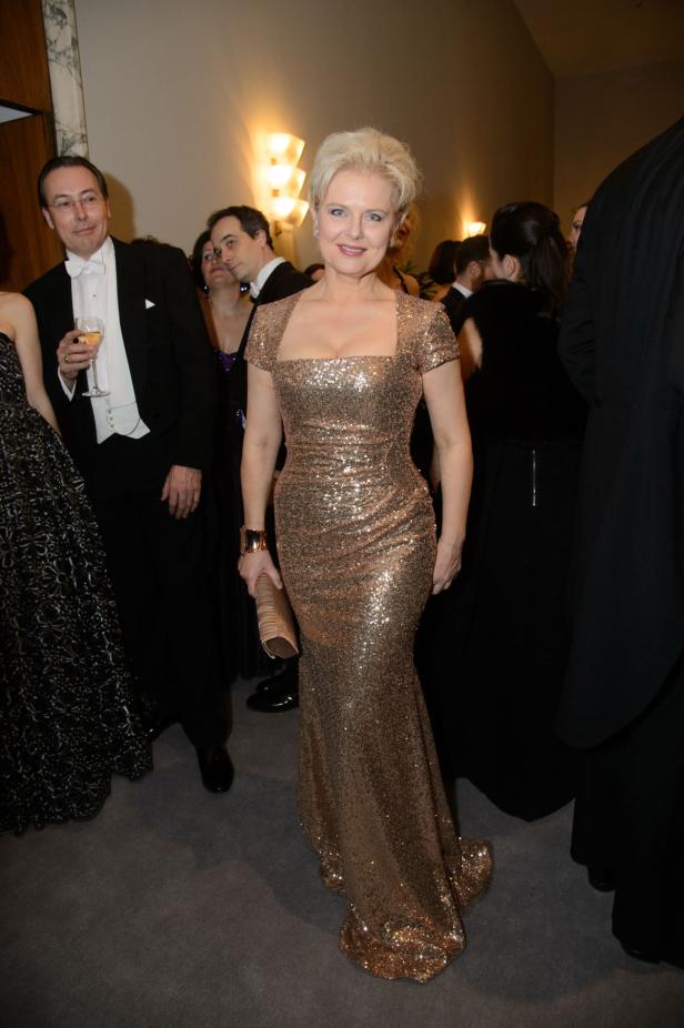 Eine Frau in einem goldenen Paillettenkleid auf einer formellen Veranstaltung.