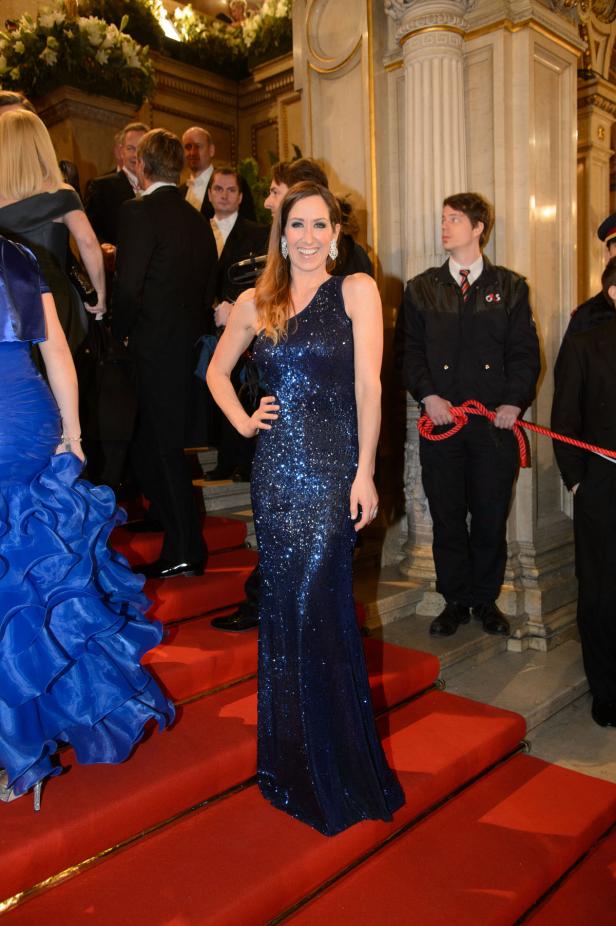 Eine Frau in einem blauen Paillettenkleid posiert auf einem roten Teppich.