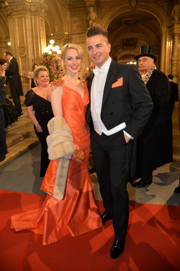 Ein Paar in Abendgarderobe auf einem roten Teppich bei einer Veranstaltung.