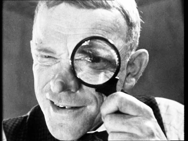 Ein Mann blickt durch eine Lupe.