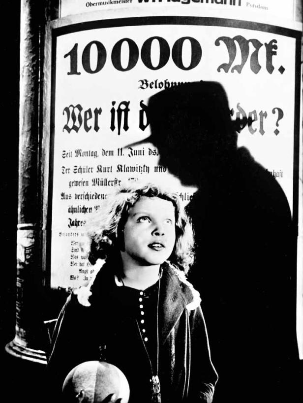 Ein junges Mädchen steht vor einem Plakat mit der Aufschrift „10000 Mark Belohnung“.