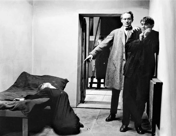 Eine Szene aus dem Film „Das Cabinet des Dr. Caligari“ mit einer scheinbar toten Frau und zwei Männern.