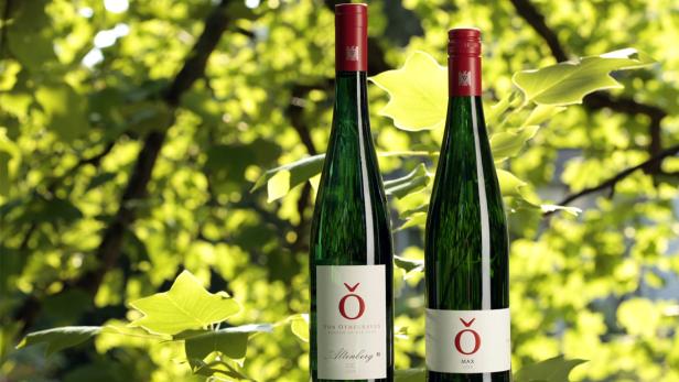 Zwei Flaschen Weißwein der Marke Von Othegraven vor einem Hintergrund aus Blättern.