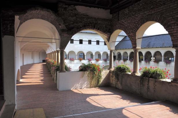 Ein Arkadengang mit roten Blumenkästen in einem Schlossgarten.