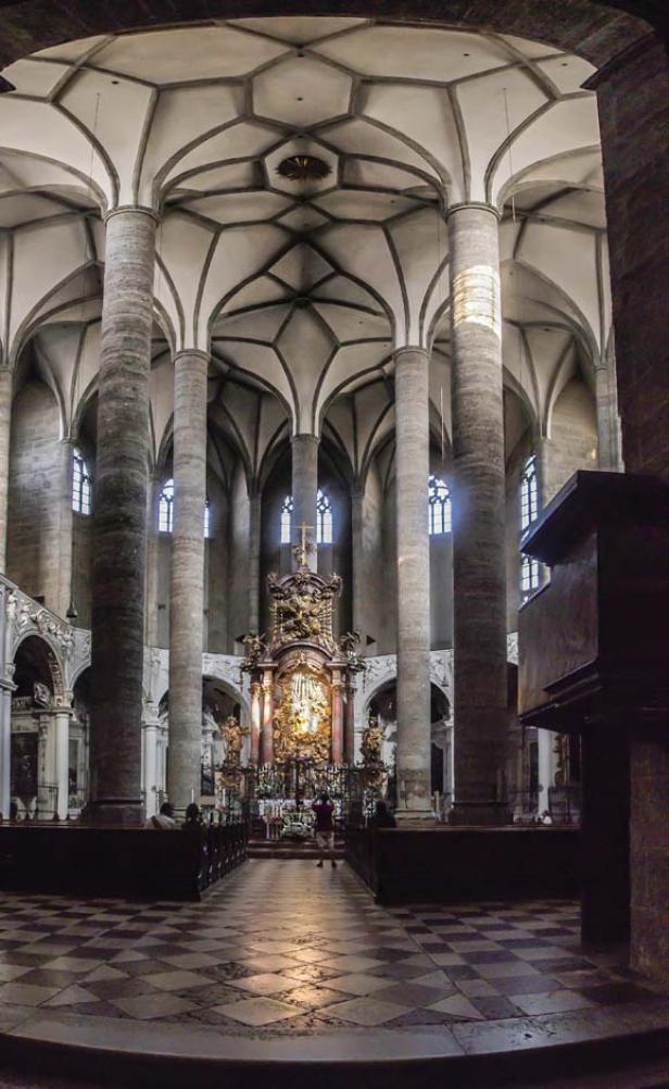Innenansicht einer Kirche mit hohen Säulen und einem verzierten Altar.
