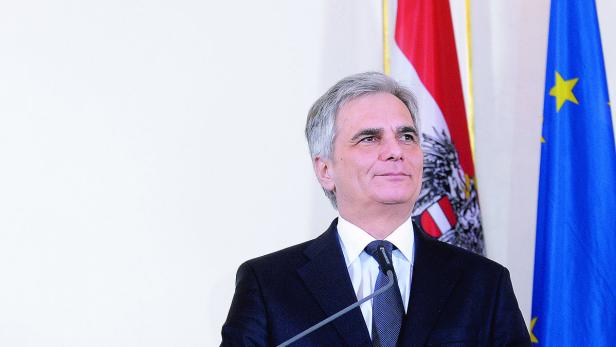 Ein Mann in einem Anzug steht vor der österreichischen und der EU-Flagge.