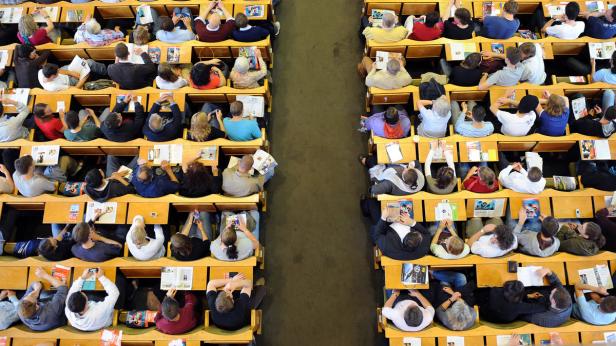 Ein Hörsaal gefüllt mit Studierenden, die an ihren Tischen sitzen und lernen.
